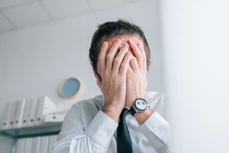 Business failure, businessman covering face with hands and crying in office, selective focus