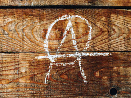 Anarchist symbol on wooden wall written in chalkの写真素材