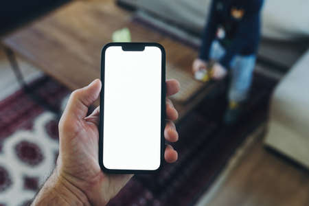Smartphone mockup, internet of things and smart home concept, man using mobile phone. Close up of hand holding device with blank screen in home interior.の写真素材