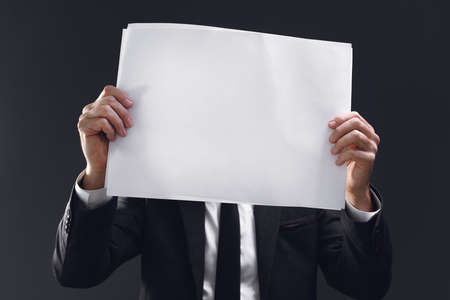 Businessman holding blank poster paper as mockup copy space for text of graphics, selective focusの写真素材