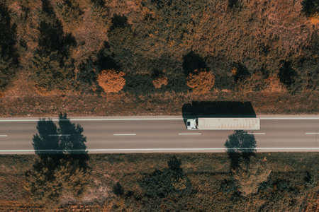 Aerial shot of freight transportation truck on road in summer afternoon, top down drone image of...