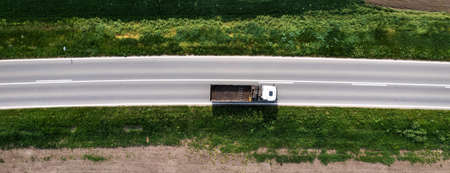 Top view aerial of semi-end dump truck with empty trailer on the road, drone pov