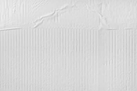 Crumpled white advertising poster paper glued on the wall as copy space and background. Graphic...