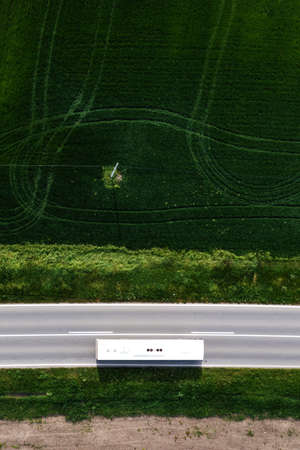 Aerial shot of shuttle bus driving along the highway through cultivated landscape, drone pov directly aboveの写真素材