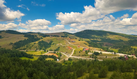 Beautiful Zlatibor landscape with houses scattered over green hills on sunny summer day seen from cable car gondolaの写真素材