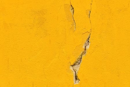 Damaged cracked yellow concrete wall as background and copy spaceの写真素材