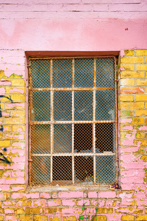Old grid windows with broken glass on exterior wall of an old abandoned factory warehouse buildingの写真素材