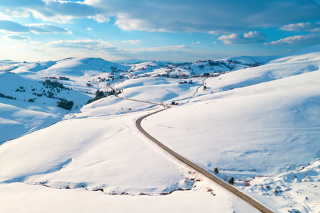 Aerial shot of empty road and frozen mountain creek in winter landscape at Zlatibor, Serbiaの写真素材