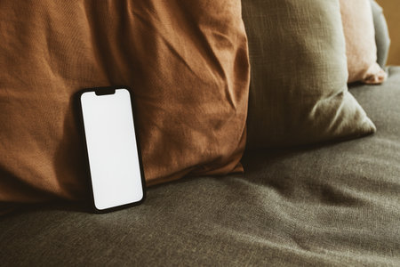 Smart mobile phone device with blank white mockup screen on living room sofa, selective focusの写真素材