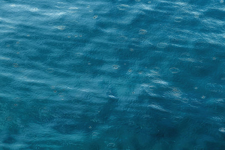 Drizzle rain concentric circles on sea water surface during stormの写真素材