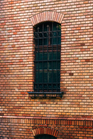 Old vintage brick wall and window with protective metal bars on a buildingの写真素材