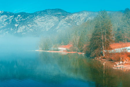 Lake Bohinj landscape in winter morning, fog rising over clean glacial water in slovenian national park Triglav and famous travel destinationの写真素材