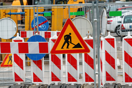 Men at work road sign at construction site during city street road maintenance, selective focusの写真素材