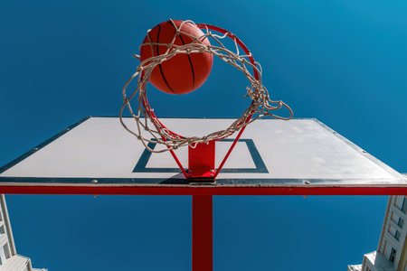 Low angle view of ball falling through hoops at outdoor basketball court, selective focusの写真素材