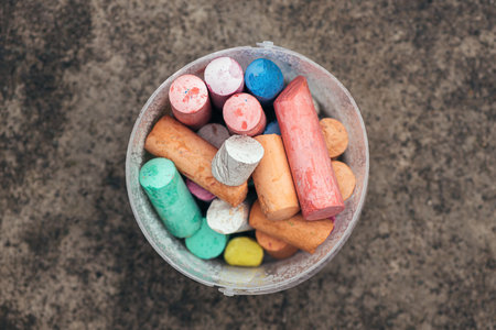Top view of colorful drawing chalk sticks in plastic bucket, selective focus