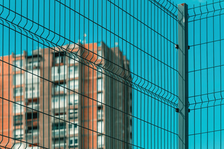 High rise architectural brutalism style apartment building behind metal fence, selective focus