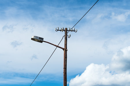 Old street light lamp and electricity pole against blue skyの写真素材