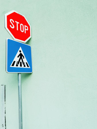 Stop and pedestrian crossing traffic sign leaning on to wall as copy space and background