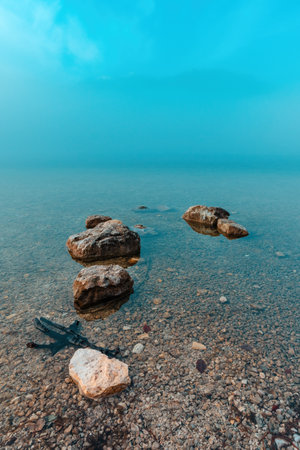Rocks in Bohinj lake in foggy winter morning, selective focus