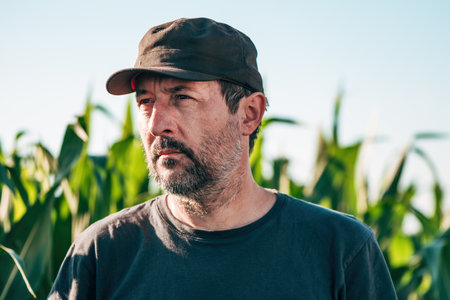 Headshot portrait of male farm worker in cultivated corn crop field, selective focus