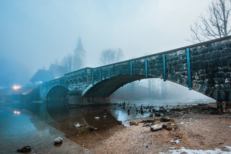 Old stone bridge at Bohinj lake in foggy morning, tranquil scene from Slovenia's travel destination in dawn, selective focusの写真素材