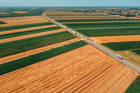 Aerial view of traffic on the highway through cultivated landscape in summer, drone pov