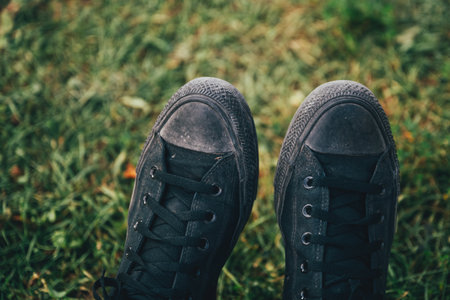 Dirty black sneakers shoes on grass, selective focus