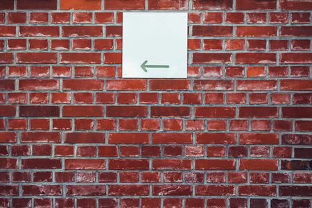 Direction arrow sign board on brick wall facade with copy space