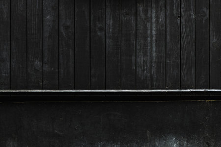 Dark black wood and concrete background, old worn facade surface texture as graphic design elementの写真素材