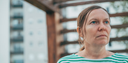 Headshot portrait of serious female person with small ponytail hairstyle looking into distance, selective focusの写真素材