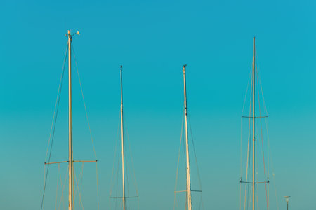 Boat masts against blue sky in summer morning
