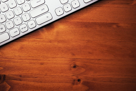 Modern white metallic personal computer keyboard on brown office desk, top view with copy spaceの写真素材