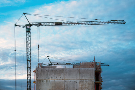 Tall prefabricated residential building construction site with old crane, selective focusの写真素材