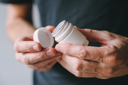 Closeup of male hands with plastic medicine jar, selective focus