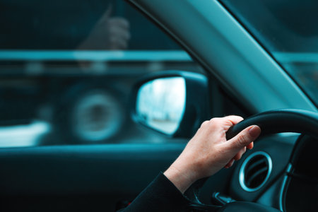 Getting away from it all concept, closeup of female hand on car steering wheel, woman driving vehicle along the road and passing by semi-truck, selective focusの写真素材