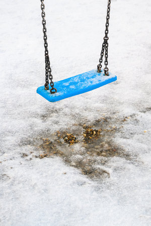 Frozen swing on children playground in winter, selective focusの写真素材