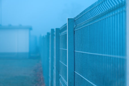 Steel metal fencing in foggy winter morning, selective focusの写真素材