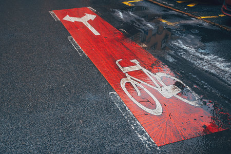 Bicycle lane with direction arrow signs on asphalt road on a rainy day, selective focusの写真素材