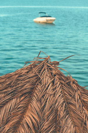 Dry palm leaf beach parasol for sun protection at seaside during summer holiday, selective focusの写真素材