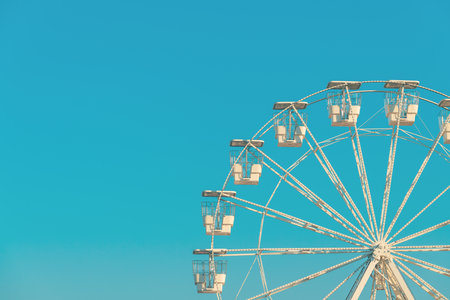 Giant white observation ferris wheel for panoramic view in amusement park is popular entertaining ride, shot against blue sky on bright sunny day, copy space includedの写真素材