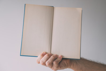Hardcover book mockup blank pages, male hand holding printed publication, selective focus