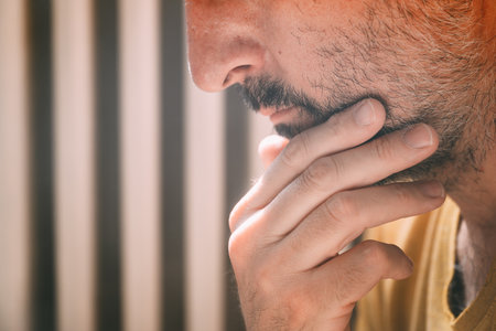 Mid adult man stroking chin and thinking, selective focus