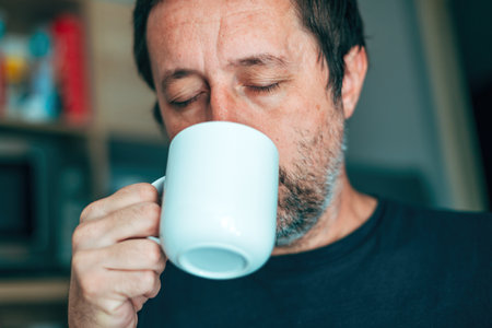 Tea time, casual adult man drinking hot tea beverage from white cup, selective focusの写真素材