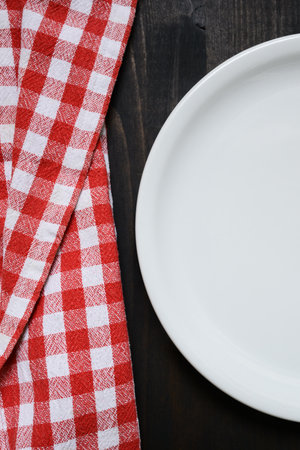 Vertical shot of flat white dinner plate on kitchen table, top viewの写真素材
