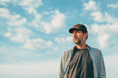 Portrait of male farm worker in field wearing trucker's hat against sunny summer sky, selective focusの写真素材