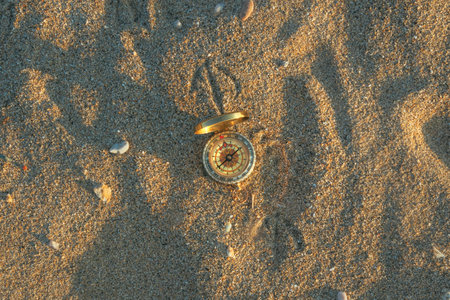 Compass in the sand, vintage navigational equipment on the beach, selective focus
