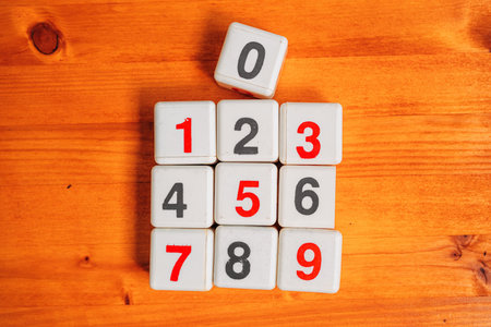 Learning numbers and mathematical calculation, top view of plastic cubes with numbers on wooden...