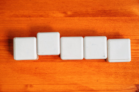 Five blank white cubes on wooden table as mockup copy space, selective focus