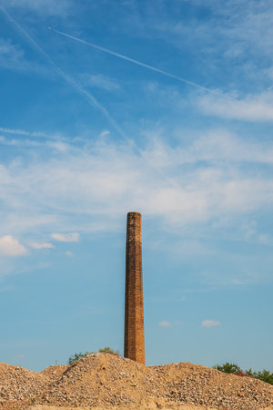 Old factory smoke stack chimney made of bricks against blue skyの写真素材
