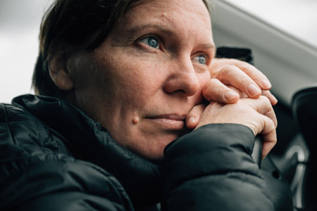 Female driver daydreaming and thinking while leaning her head against the steering wheel of a car...